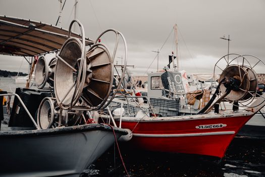 Fishing boats with equipment docked at Le Pradet, France, on an overcast day.