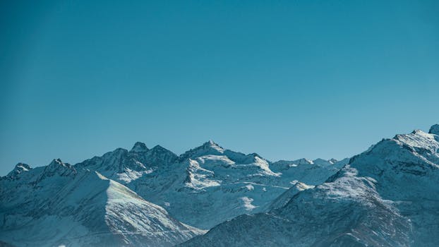 Beautiful landscape of snow-covered mountains beneath a clear blue sky.
