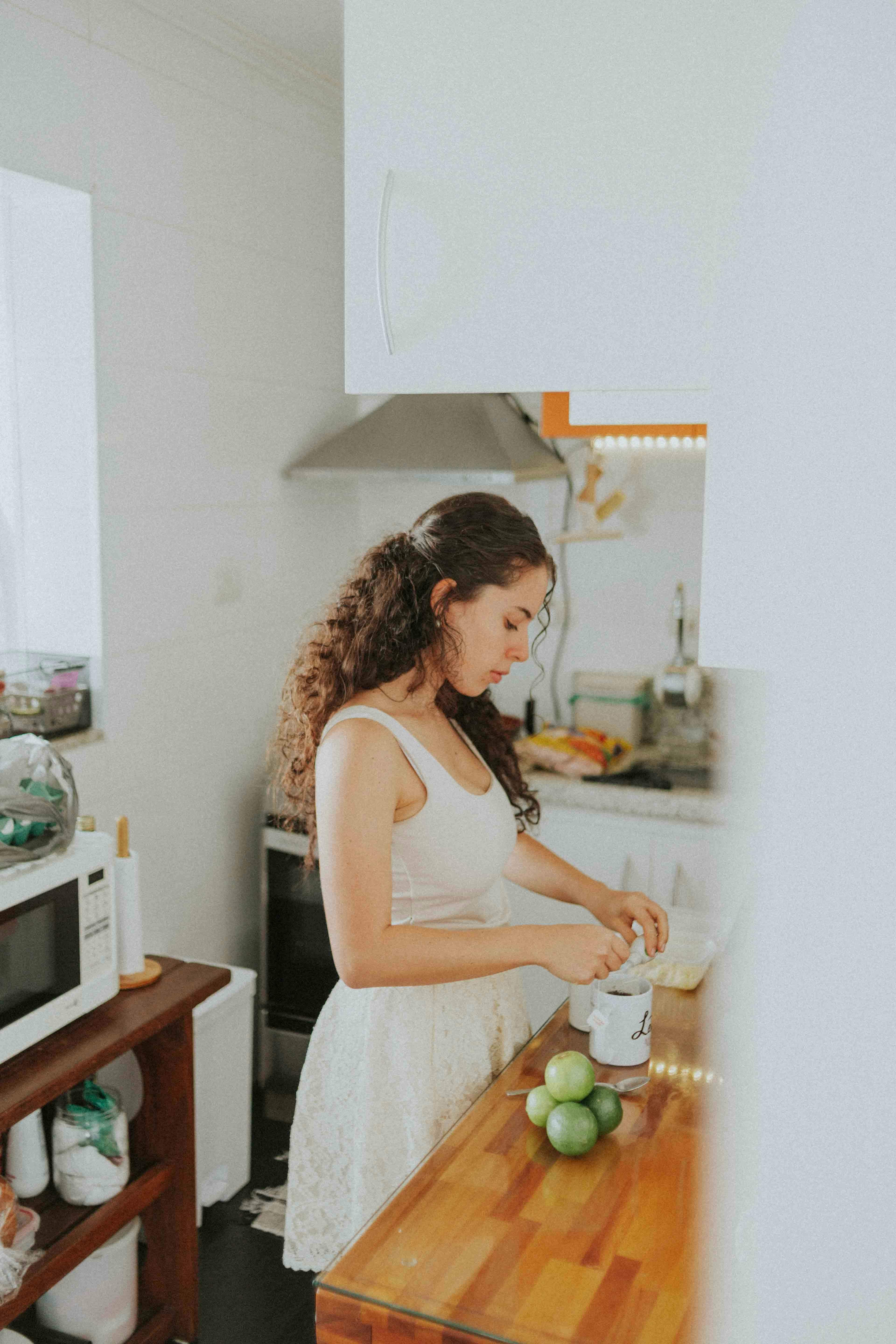 A young woman prepares food in a bright, modern kitchen, focusing on fresh ingredients and healthy cooking.