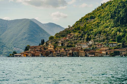 Free Picturesque view of a village by Iseo Lake, Lombardy, Italy, set against lush green mountains. Stock Photo