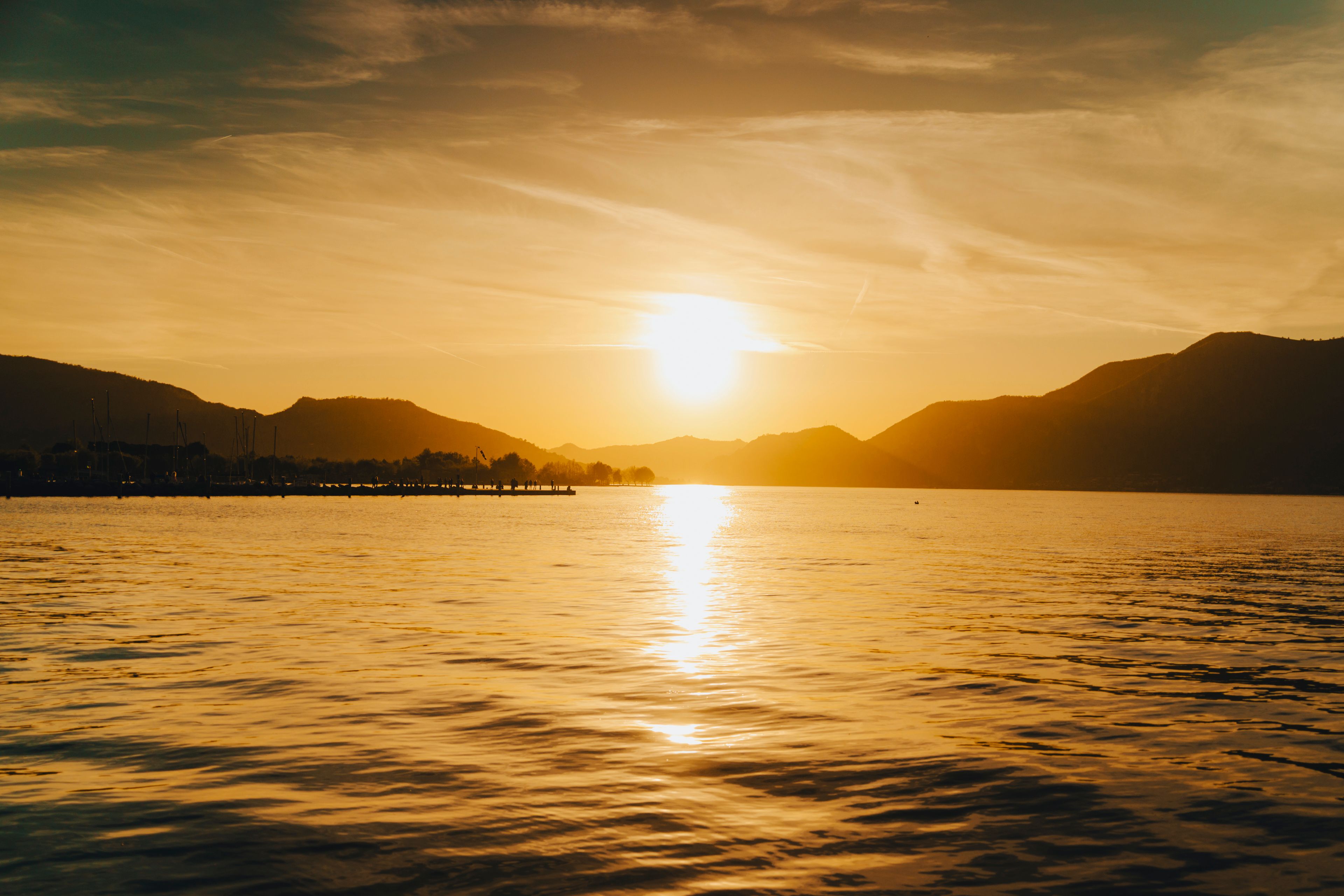 Stunning sunset over Lake Iseo with silhouetted mountains and golden reflections. - Photo by Dawid Tkocz on Pexels