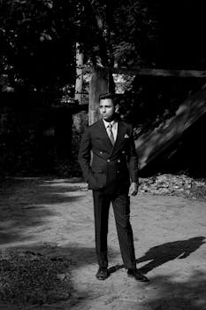 Elegant black and white portrait of a man in a suit outdoors.