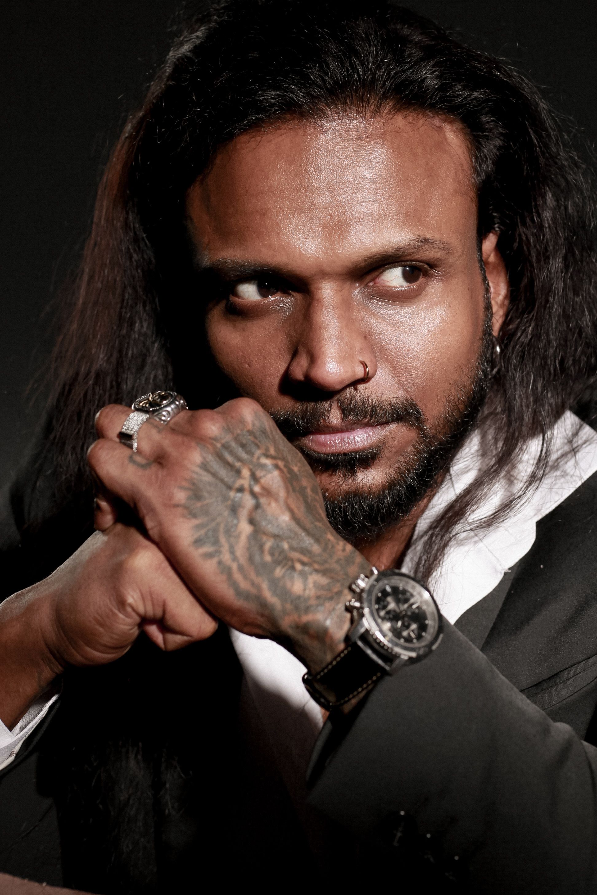 Close-up portrait of a thoughtful tattooed man in a suit, captured with a moody tone.
