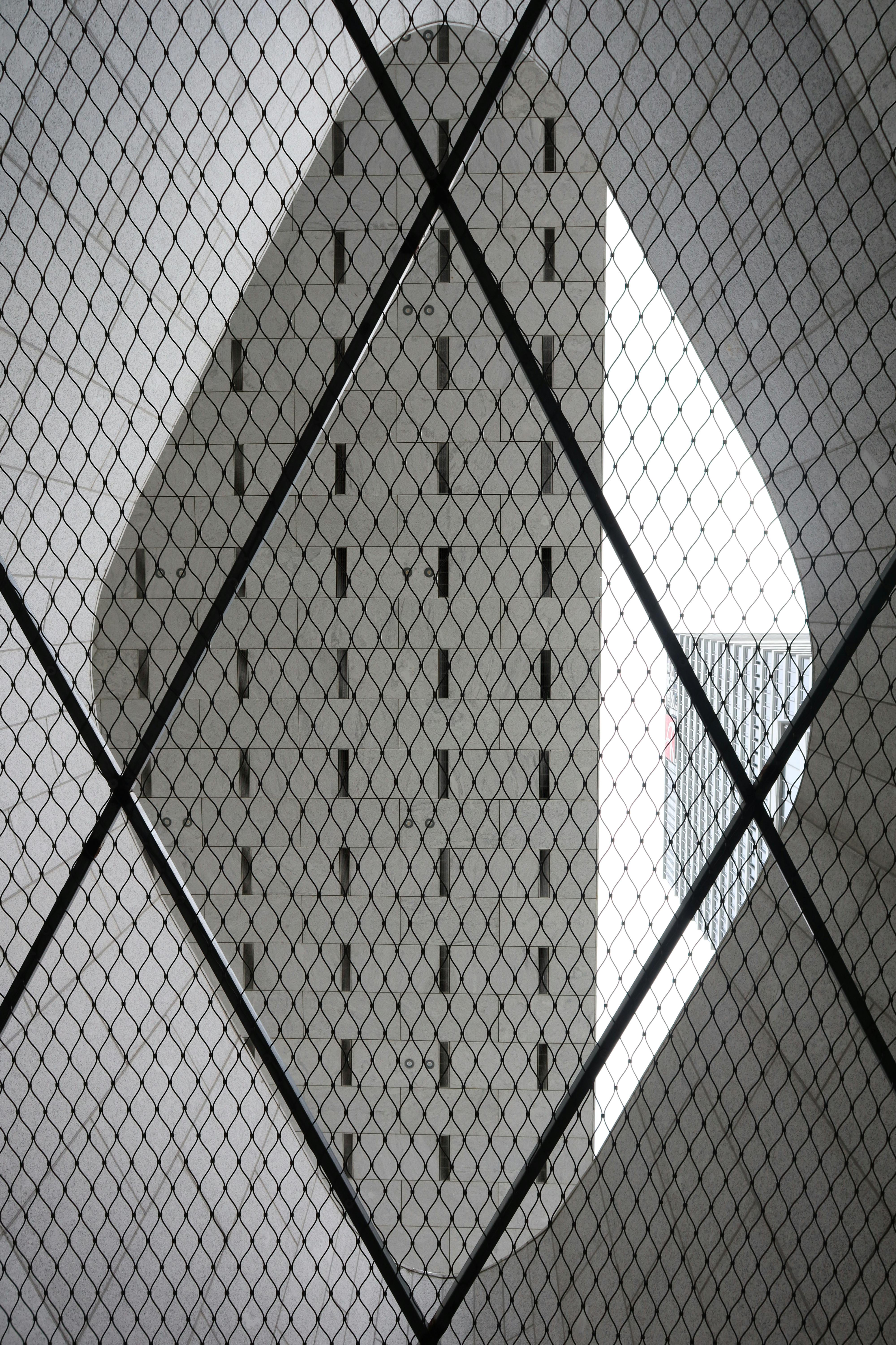 Kostenlos Urbane Architektur wird durch ein rautenförmiges Netz eingefangen, wodurch eine künstlerische Perspektive entsteht. Stock-Foto