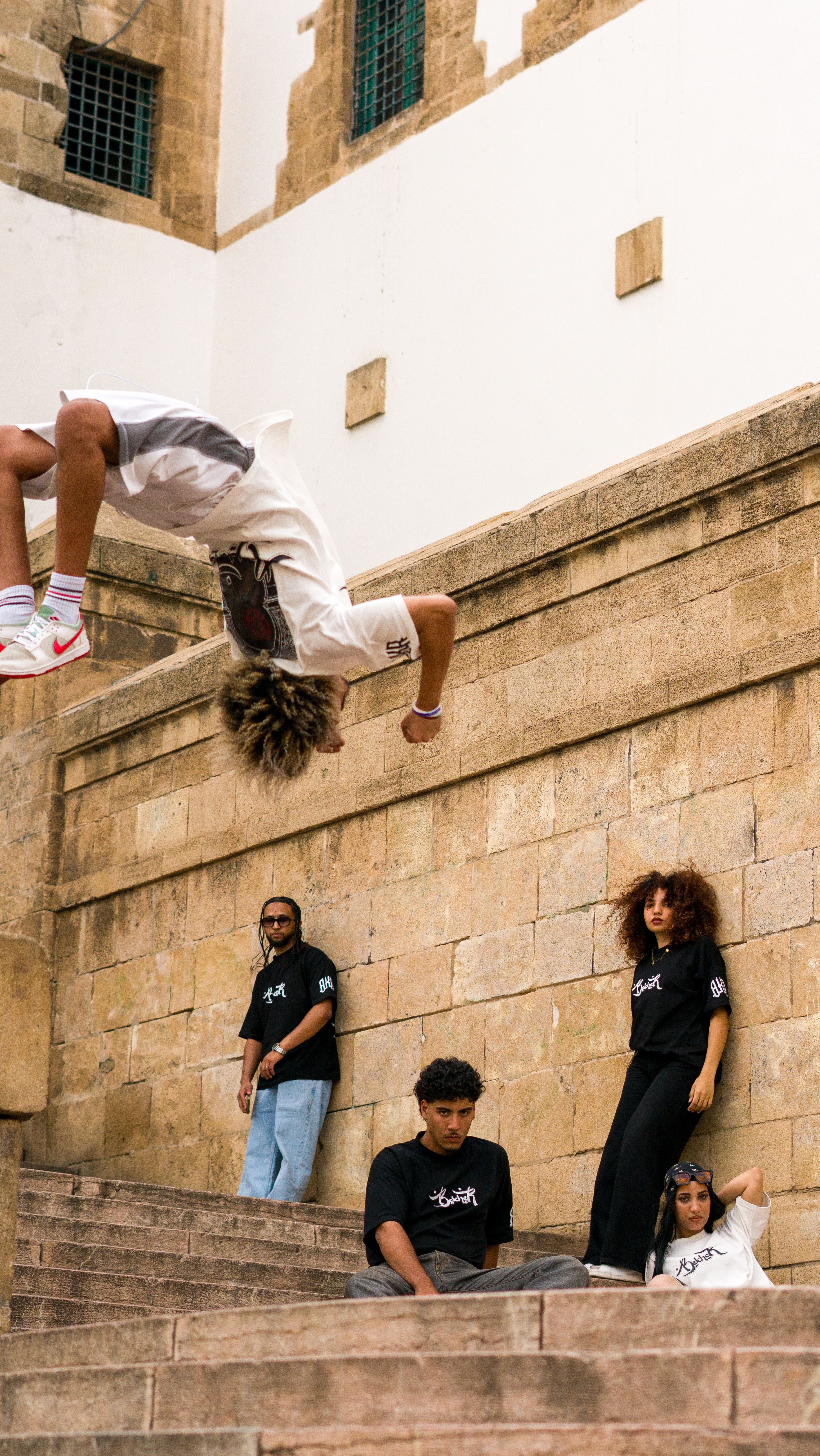 Young man performs a daring backflip on ancient stone steps while spectators watch.