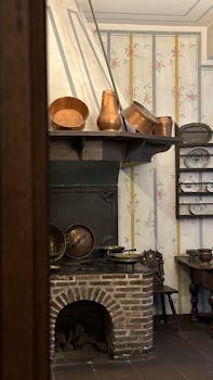 Charming vintage kitchen features brick fireplace and copper pots.