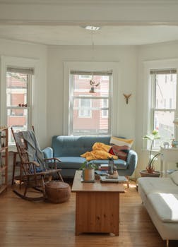 Bright and cozy living room with a blue sofa, wooden furniture, and abundant natural light.