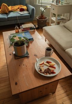 Warm living room scene with books, coffee, and snacks on a wooden table.