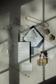 Classic flat lay of wedding invitation, jewelry, and perfume in soft lighting.