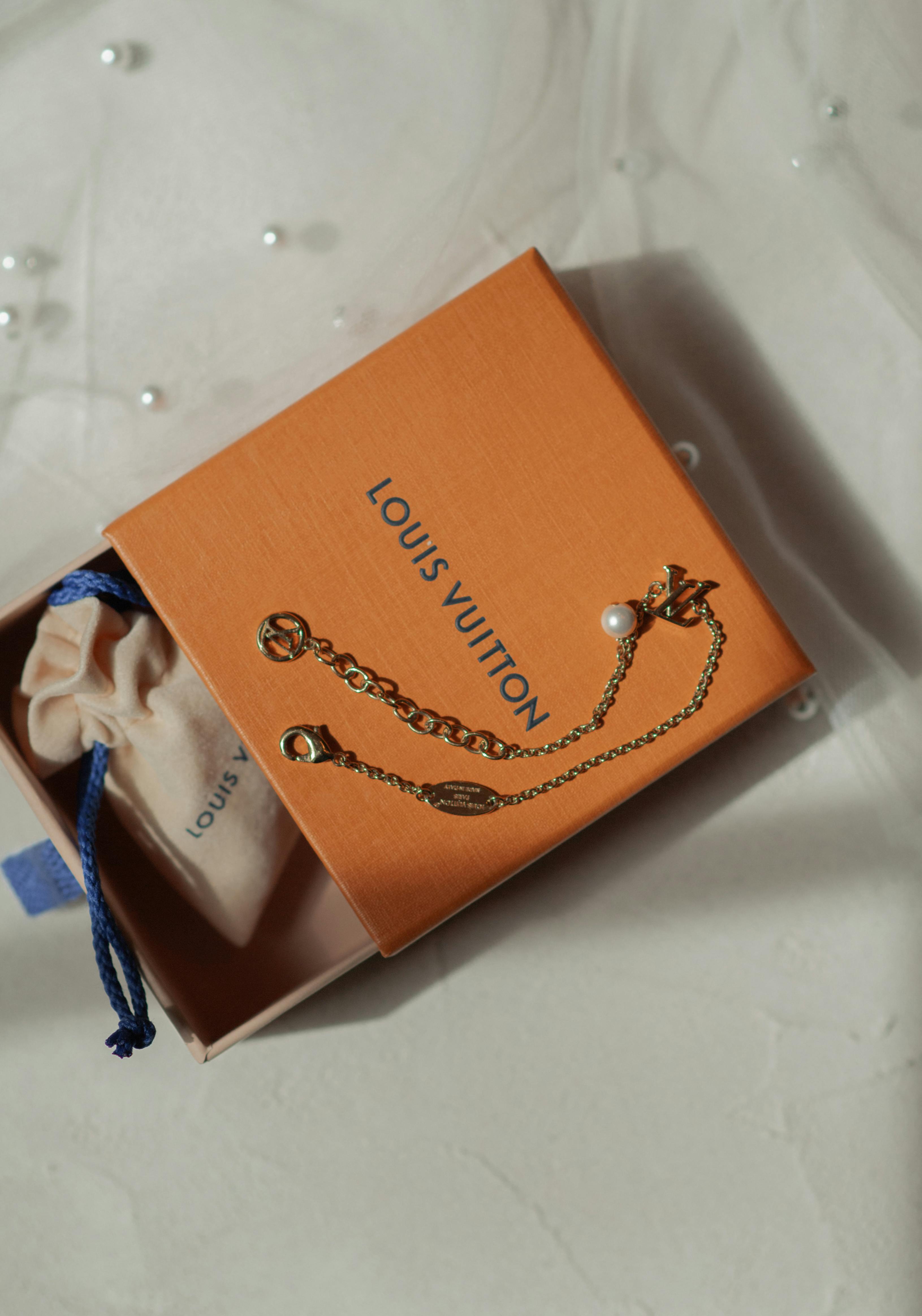 De franc Elegant estoig de joies Louis Vuitton amb polsera sobre superfície de marbre. Foto d'estoc