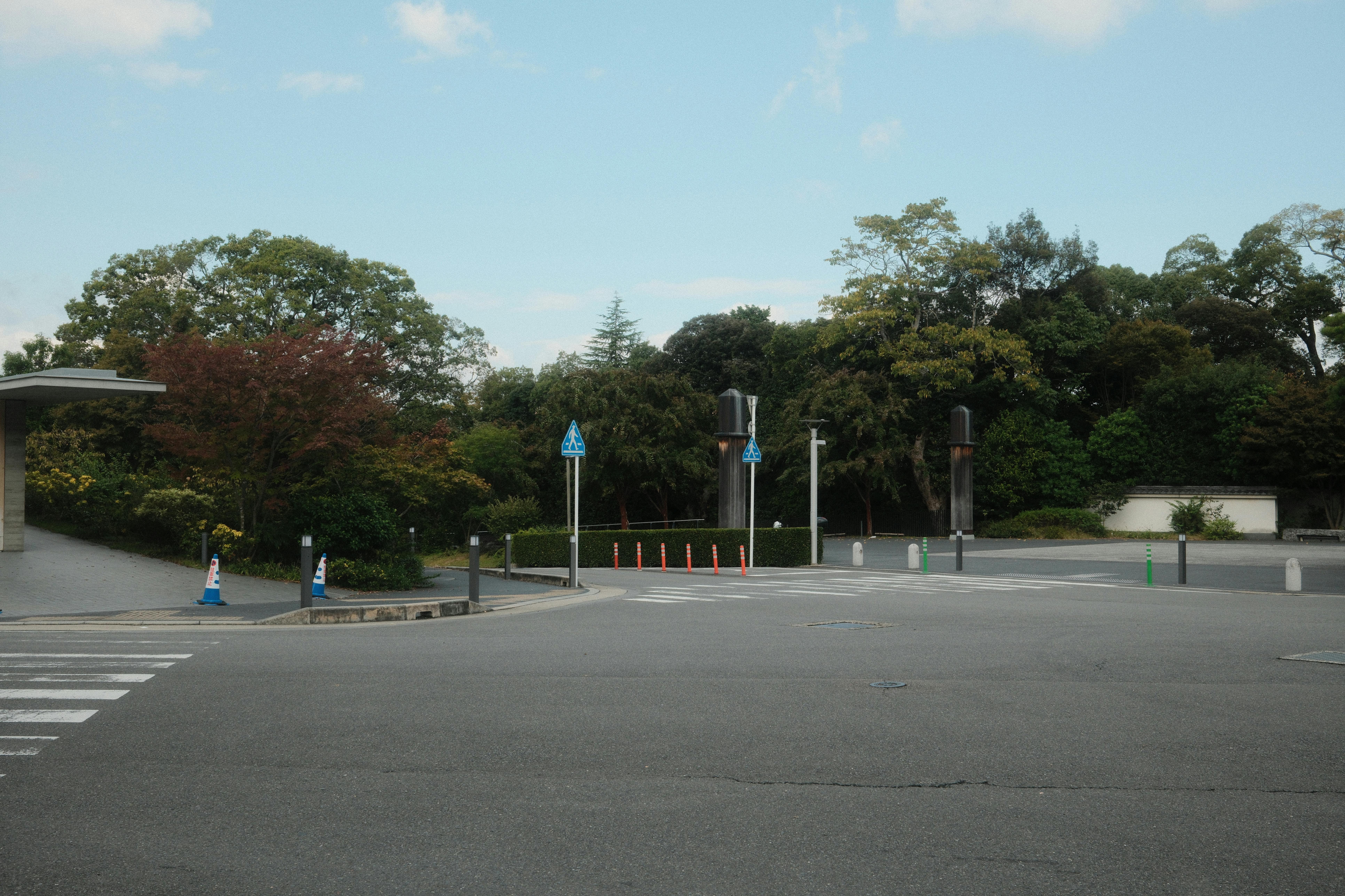 Gratis Sebuah jalan kosong di Kyoto, Jepang, yang dipenuhi pepohonan hijau subur dan langit biru cerah, menciptakan suasana perkotaan yang damai. Foto Stok