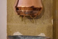 Copper water basin on rustic stone wall, reflecting traditional design.