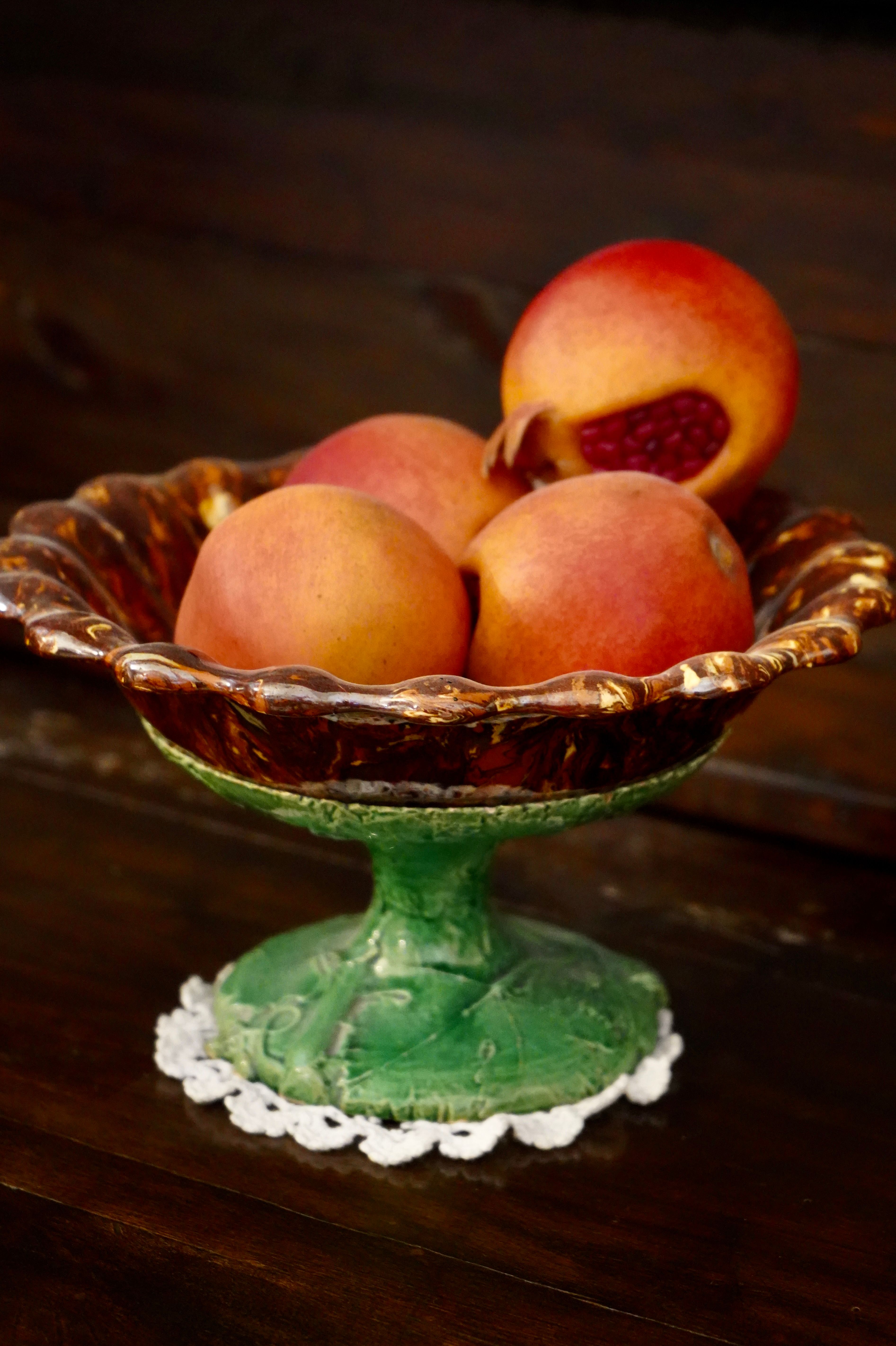 A classic ceramic bowl with ripe pomegranates on a rustic wooden table.