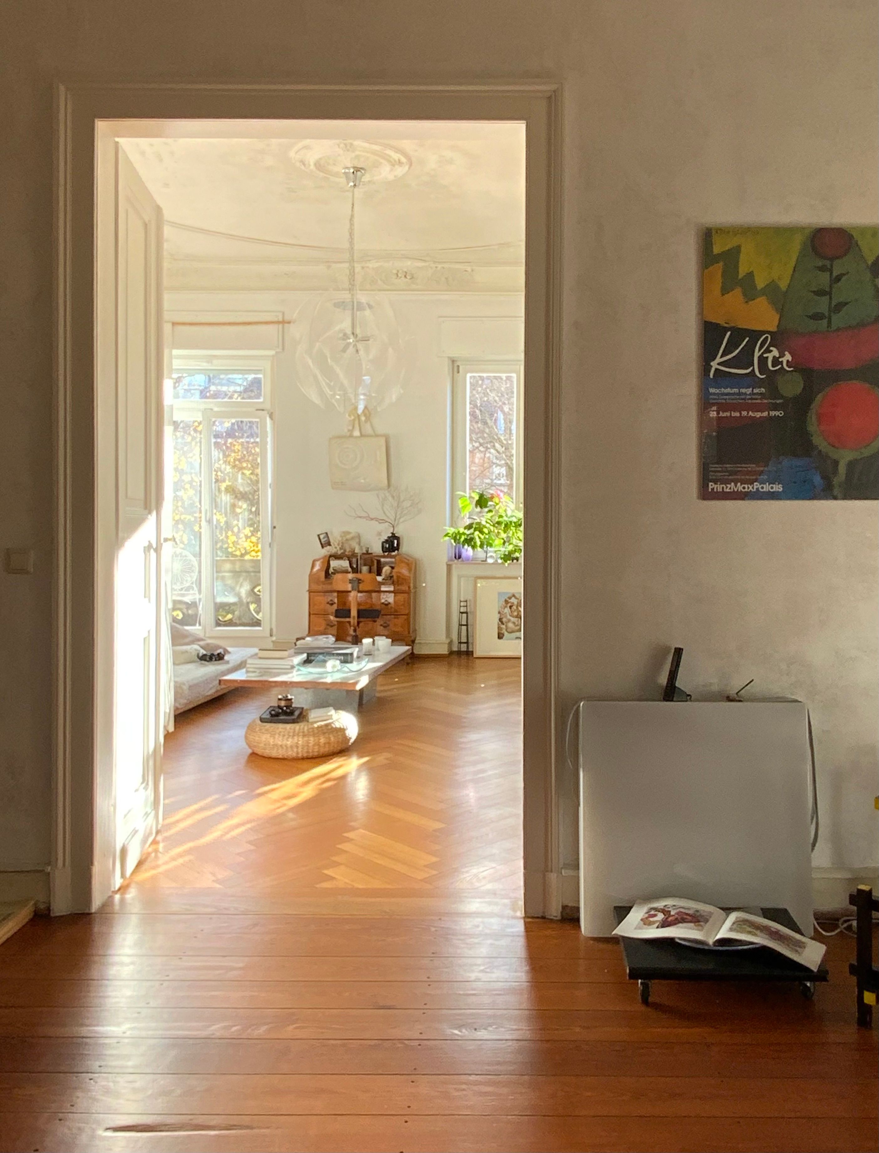A cozy, sunlit, minimalist interior featuring wooden floors and natural light.