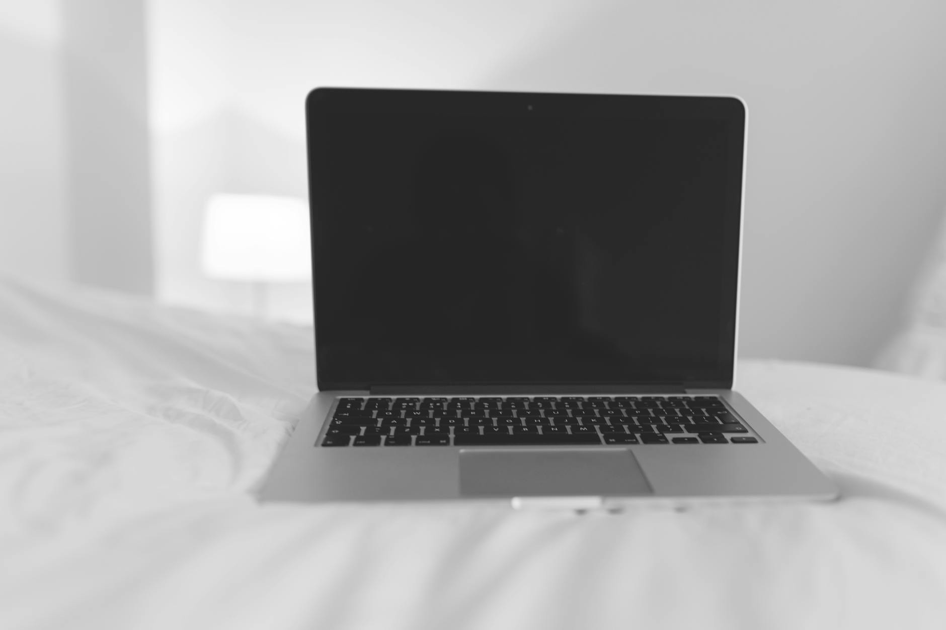 Thrifty Traveler'S Guide: Journeying On A Shoestring Budget With Couchsurfing 1 a laptop sits on a bed in a minimalist white room, perfect for remote work inspiration.