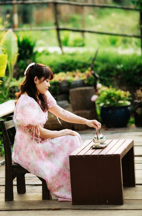 Free A serene moment of a woman in a floral dress enjoying tea in a lush garden setting in Kon Tum, Vietnam. Stock Photo