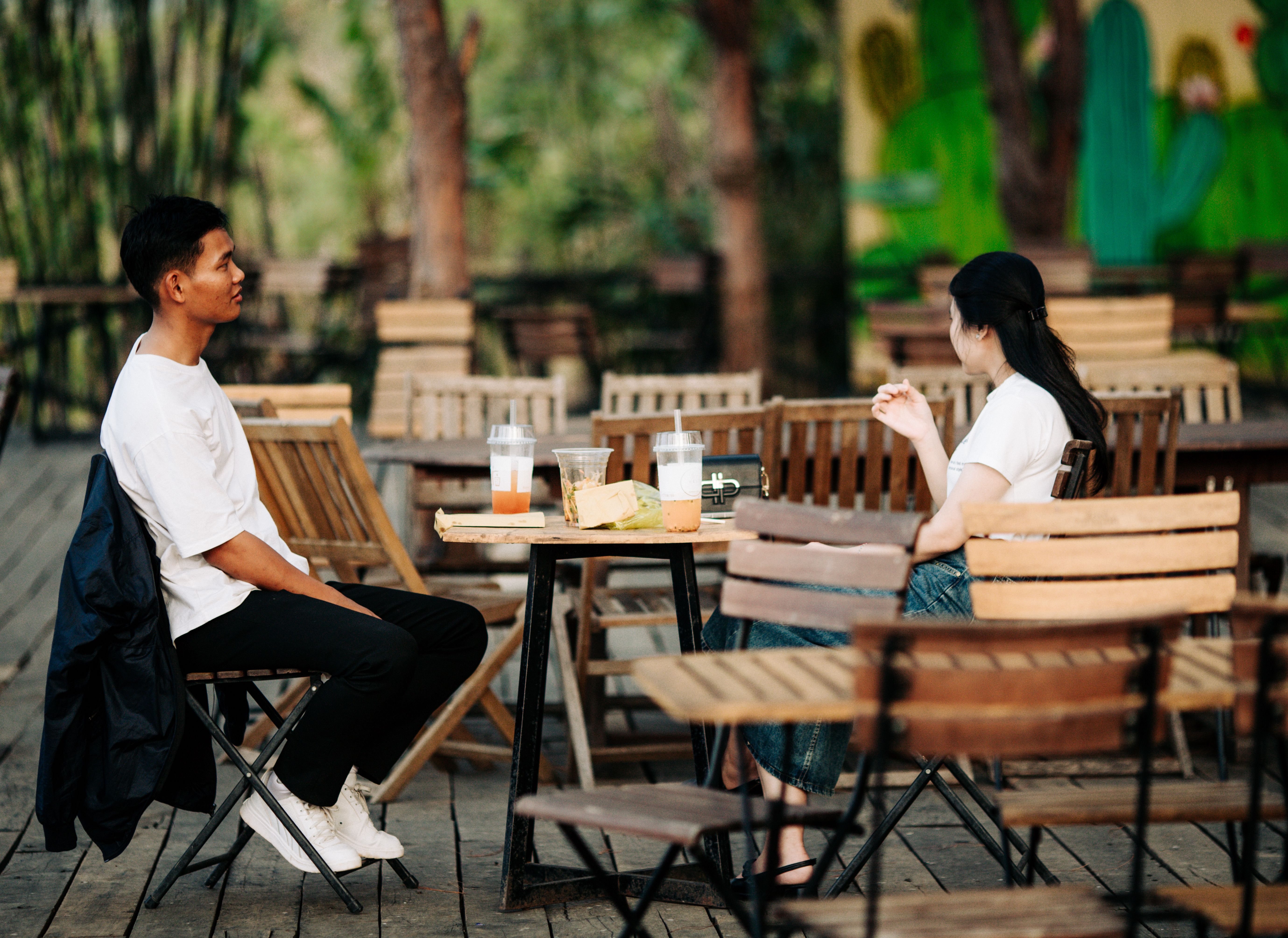 Two adults enjoying drinks at an outdoor cafe in Kon Tum, Vietnam.