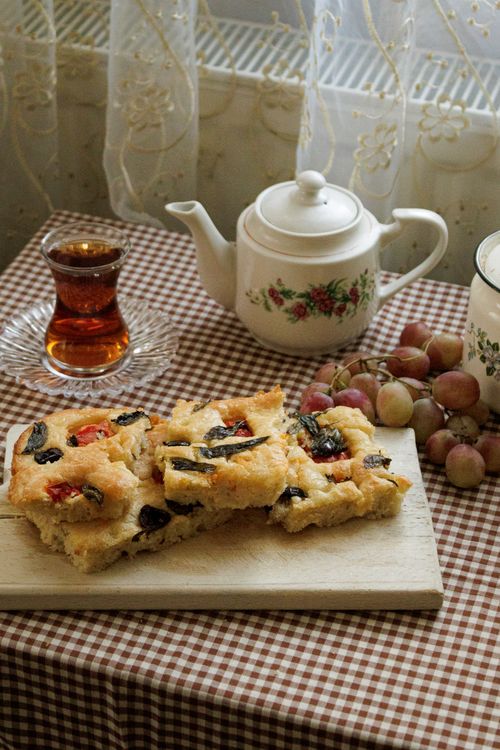 Free Inviting tea scene with homemade focaccia bread, fruit, and floral teapot on checkered tablecloth. Stock Photo