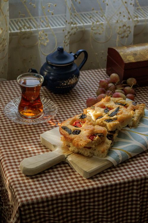 Free Cozy indoor scene featuring tea and homemade focaccia bread by window light. Stock Photo