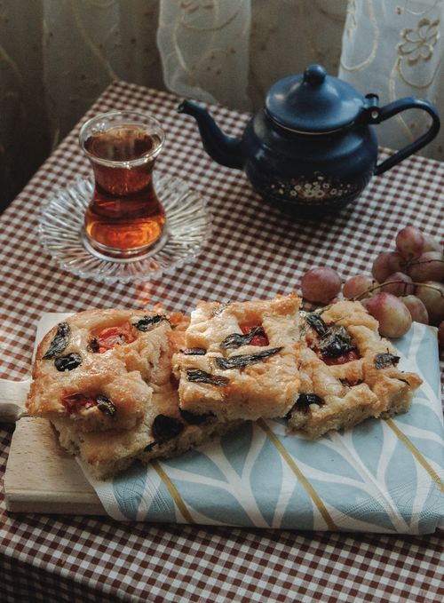 Free Cozy setup with tea, baked pastries, and grapes on a checkered tablecloth. Stock Photo