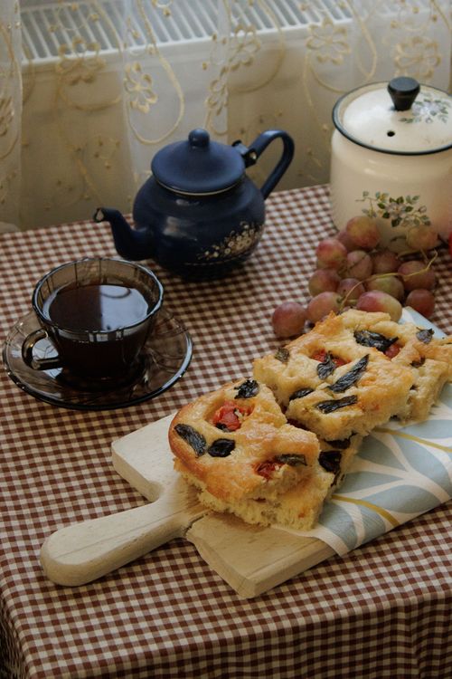 Free Cozy indoor setting featuring focaccia, grapes, and a cup of tea, ideal for rustic lifestyle themes. Stock Photo