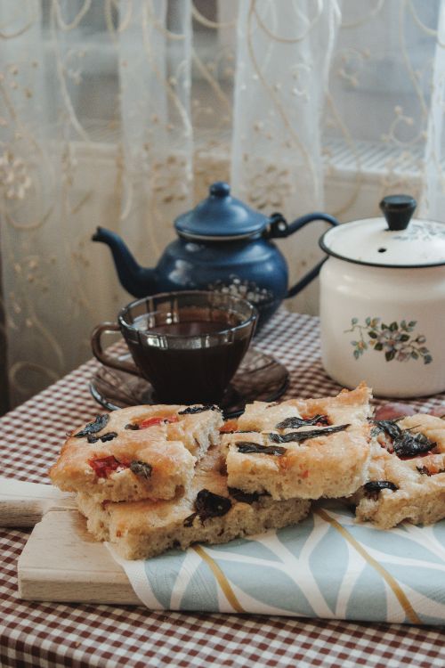 Free Cozy indoor setup with homemade focaccia, tea, and vintage kitchenware on a checkered table. Stock Photo