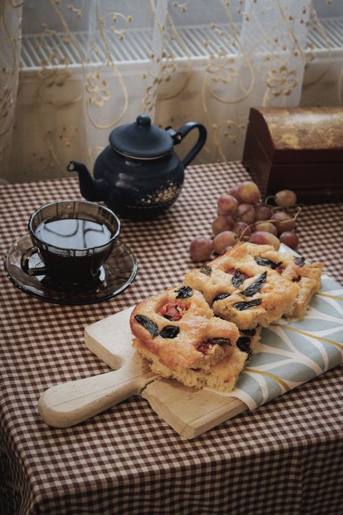 Free A cozy scene featuring tea with cake and grapes on a checkered tablecloth indoors. Stock Photo