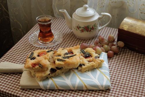 Free Cozy table setting with focaccia bread, tea, and grapes on checkered cloth. Stock Photo