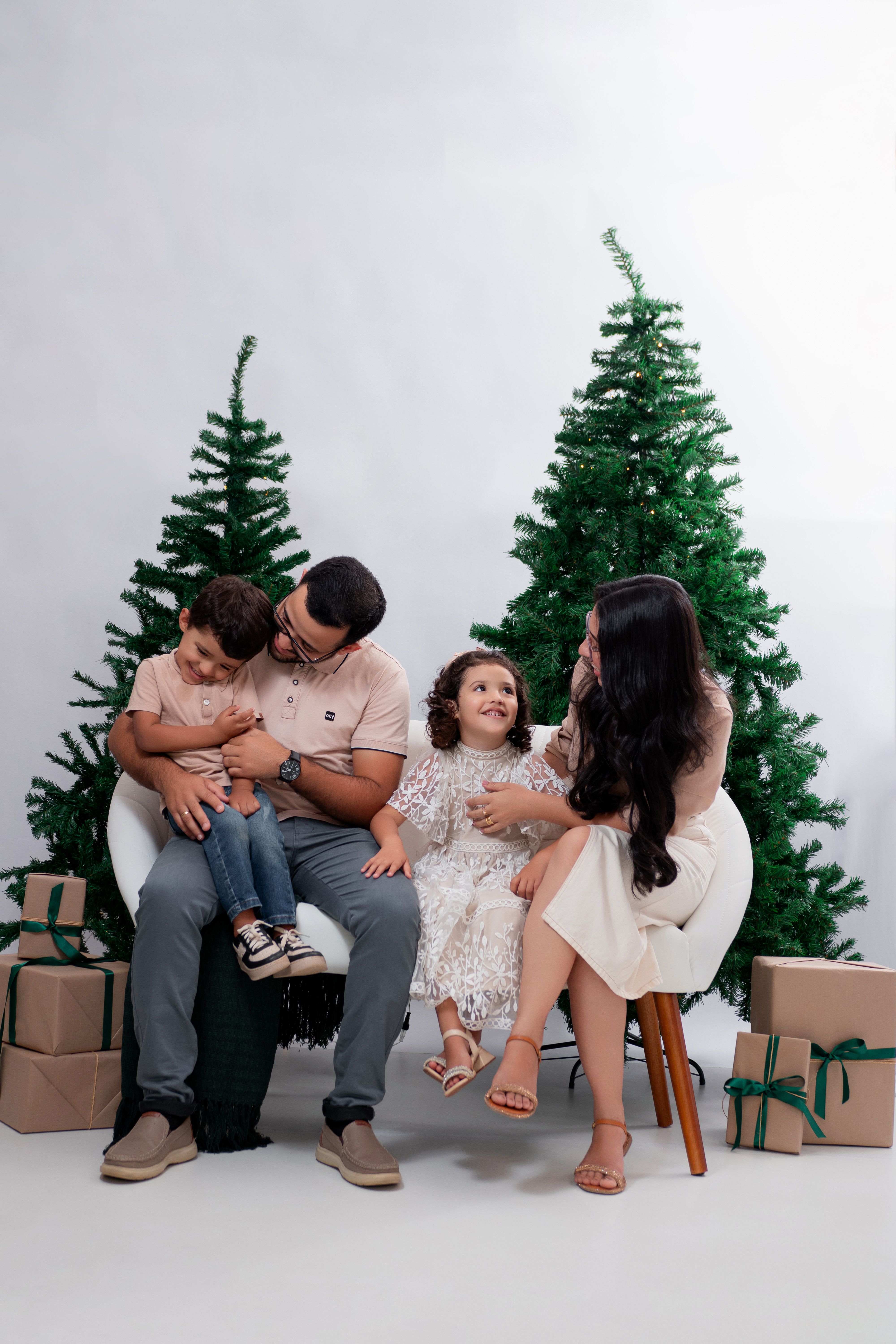Fotomural Una familia disfrutando de un ambiente navideño festivo con cajas de regalo y árboles decorados.