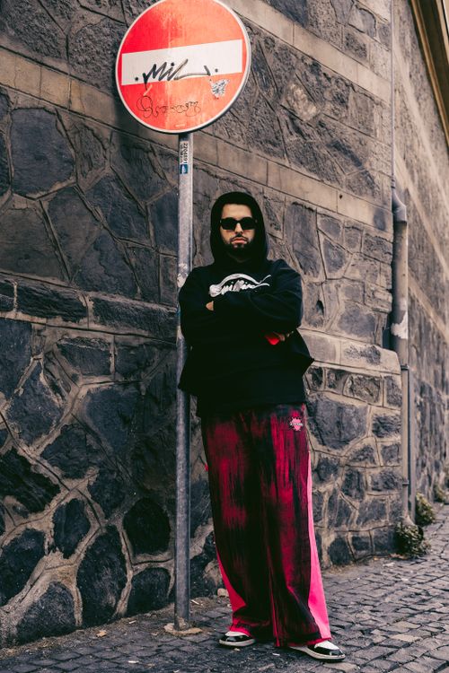 Free Stylish man in front of graffiti sign on urban street, showcasing bold streetwear fashion. Stock Photo