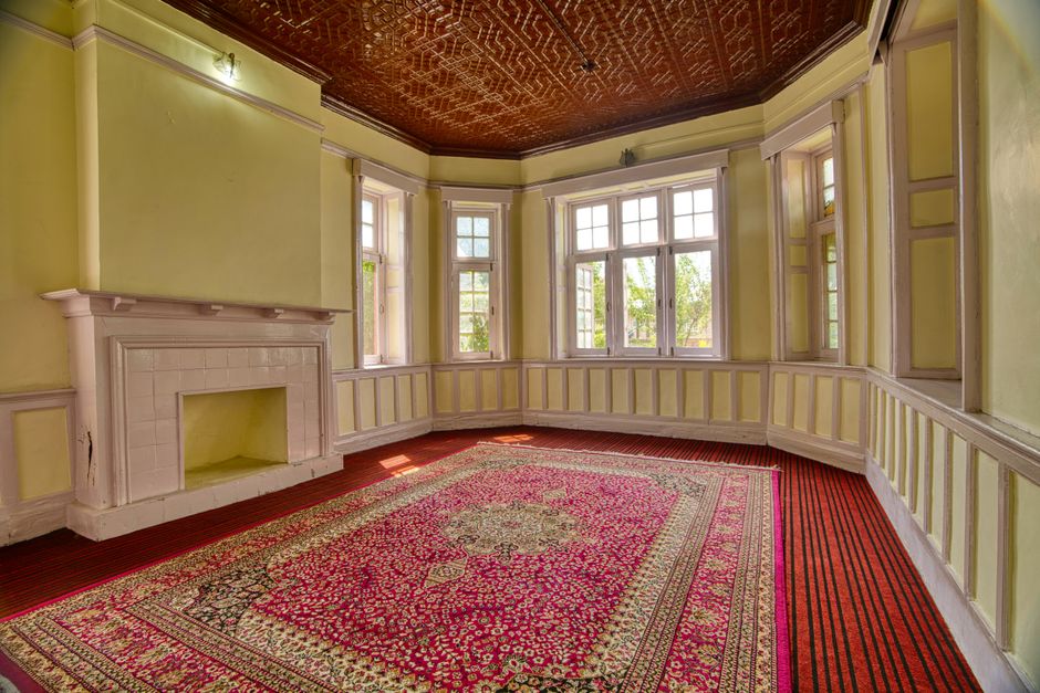 A spacious, elegant room with large windows, fireplace, and vibrant carpet in Jammu and Kashmir.