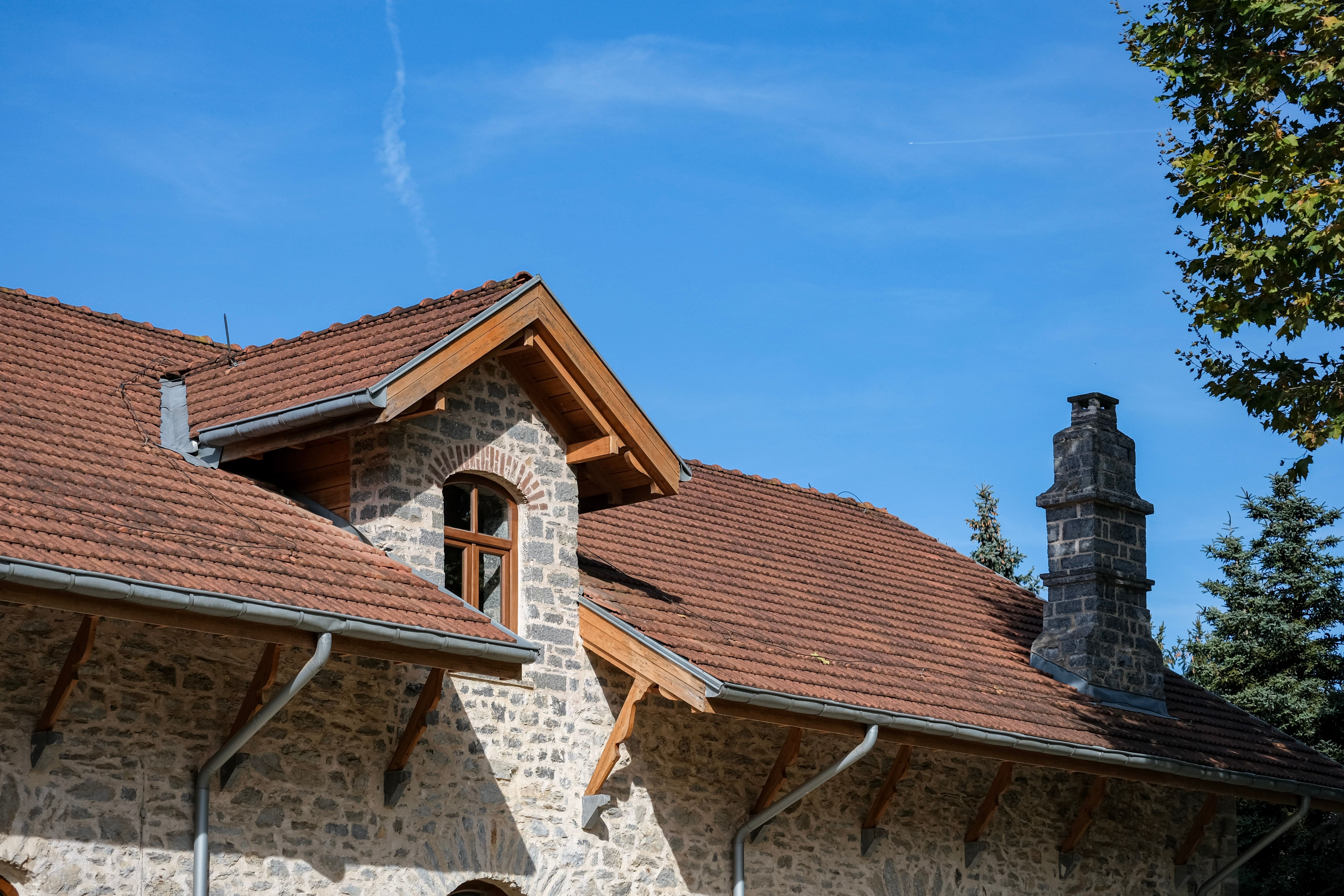 Maison rustique en pierre avec toit et cheminée rouges, sous un ciel bleu azur à Istanbul, en Turquie.