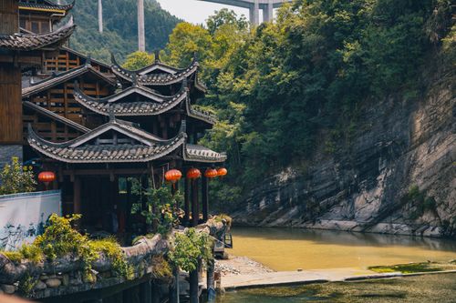 Free Beautiful wooden Asian architecture nestled by a serene river, surrounded by lush greenery. Stock Photo