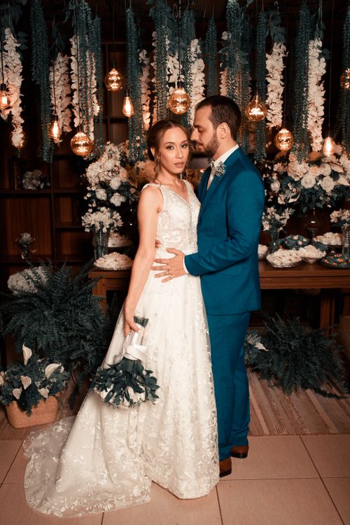 Free A bride and groom in elegant attire surrounded by floral decorations and warm lighting. Stock Photo