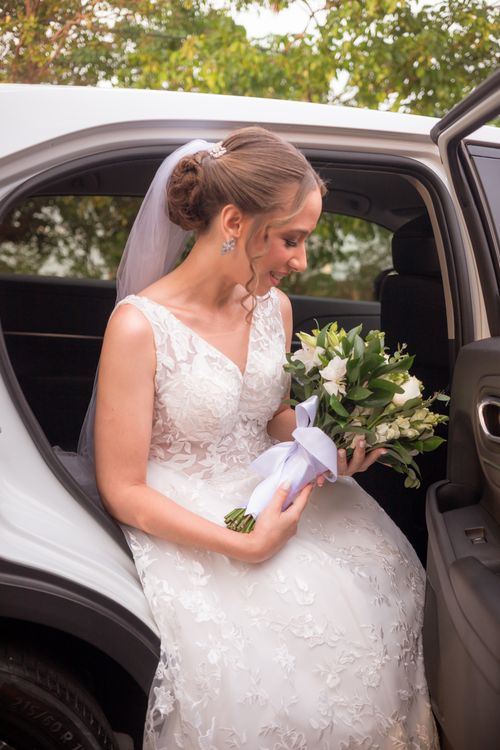 Free Bride in lace gown with floral bouquet stepping out of a car, perfect wedding moment. Stock Photo