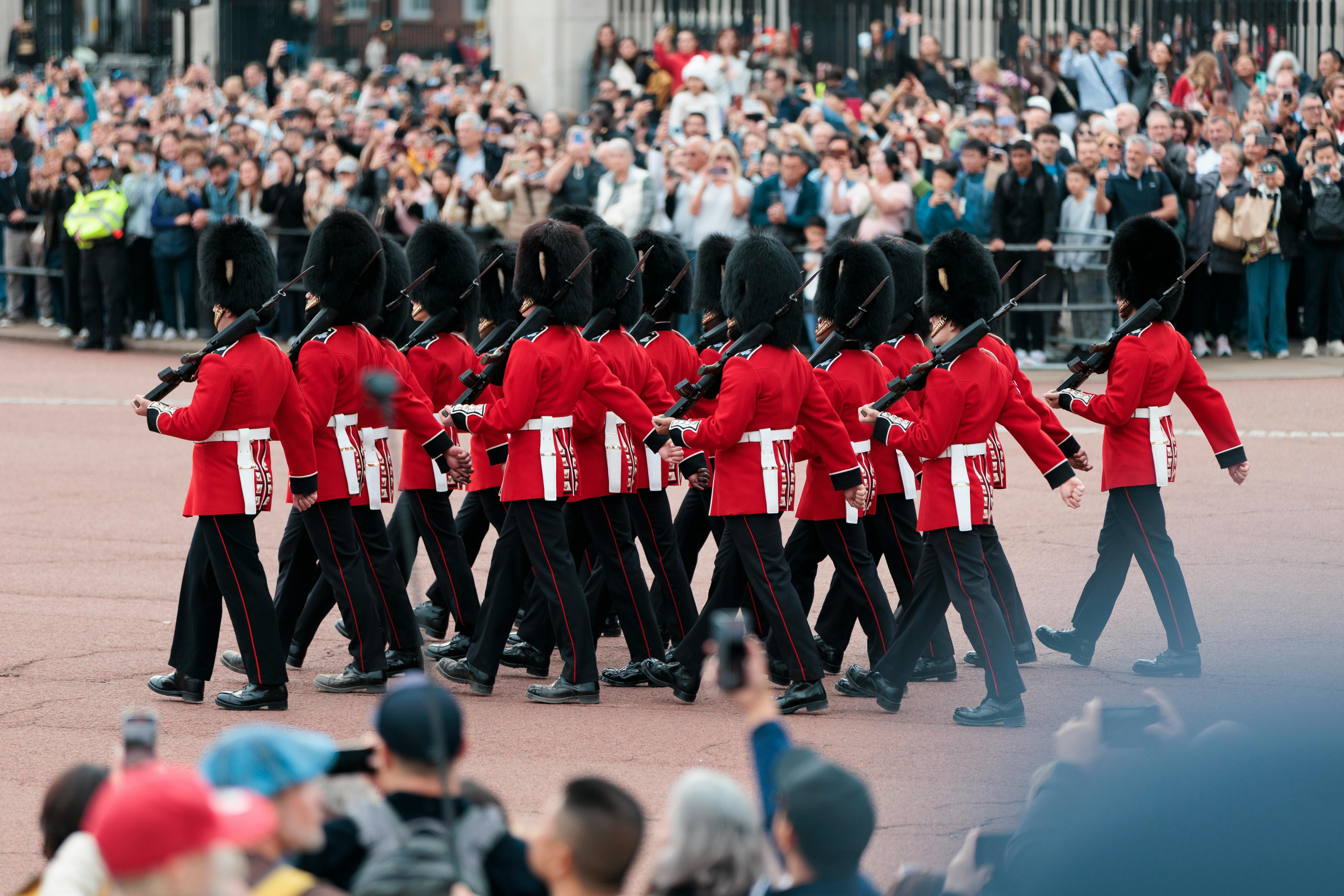 Changing of the Guard ceremony at Buckingham Palace, London, featuring soldiers in traditional red uniforms.
