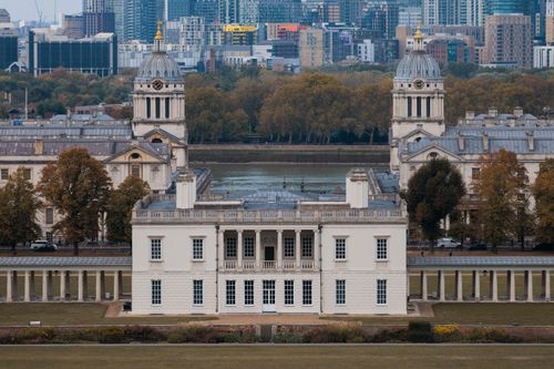 Free View of the Royal Naval College in Greenwich, London with autumnal trees and city skyline. Stock Photo