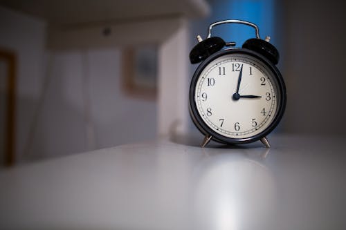 Free Black and White Alarm Clock Diplaying at 3:03 on White Wooden Surface Stock Photo