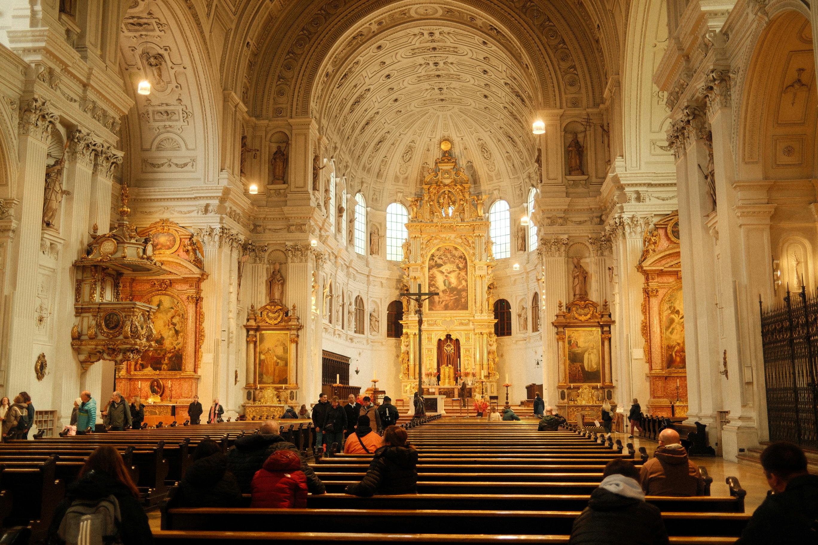 Ornate Baroque cathedral interior with visitors, highlighting stunning architecture and art decor.