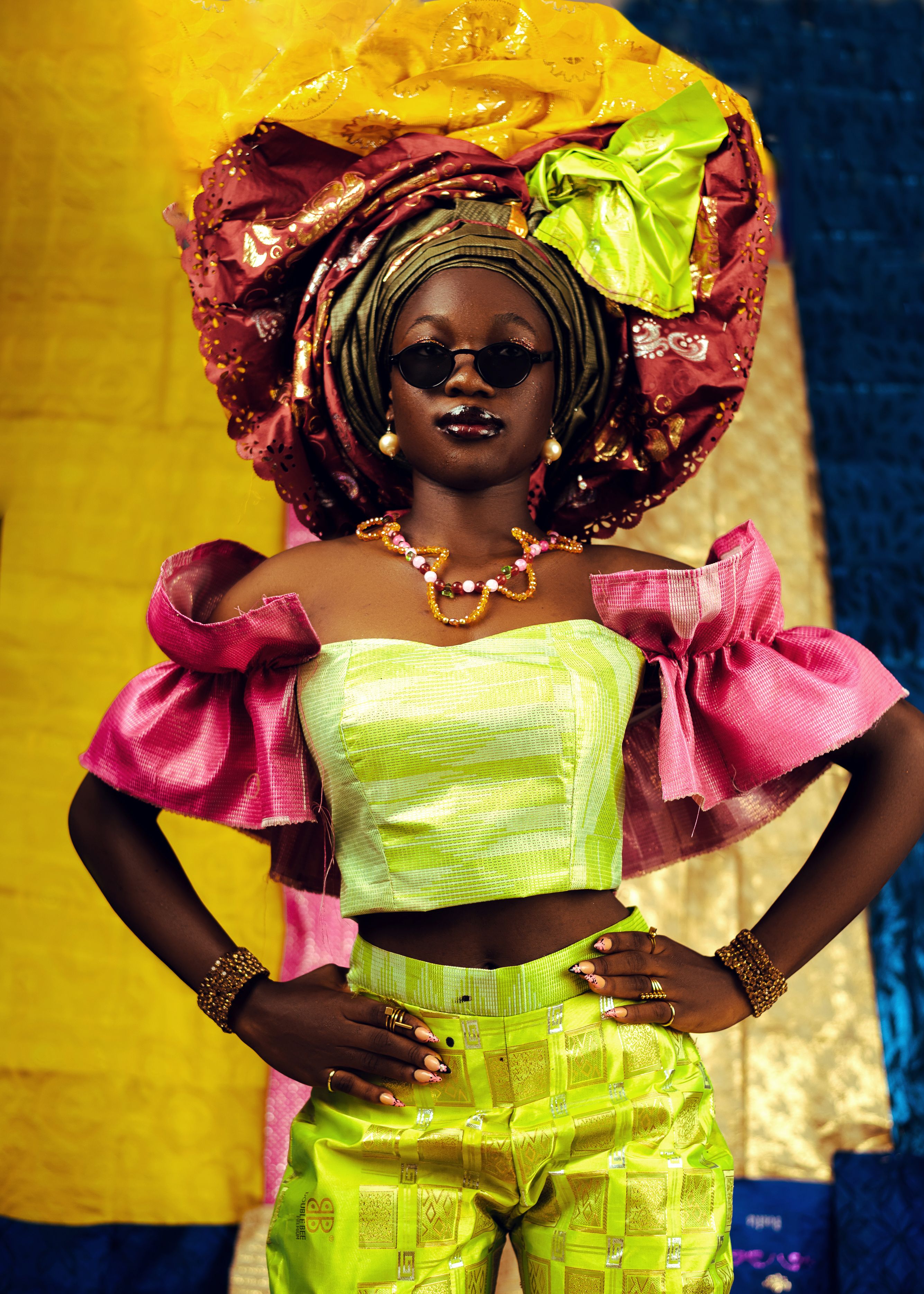 Colorful portrait of a woman in traditional African attire with Gele headwrap.