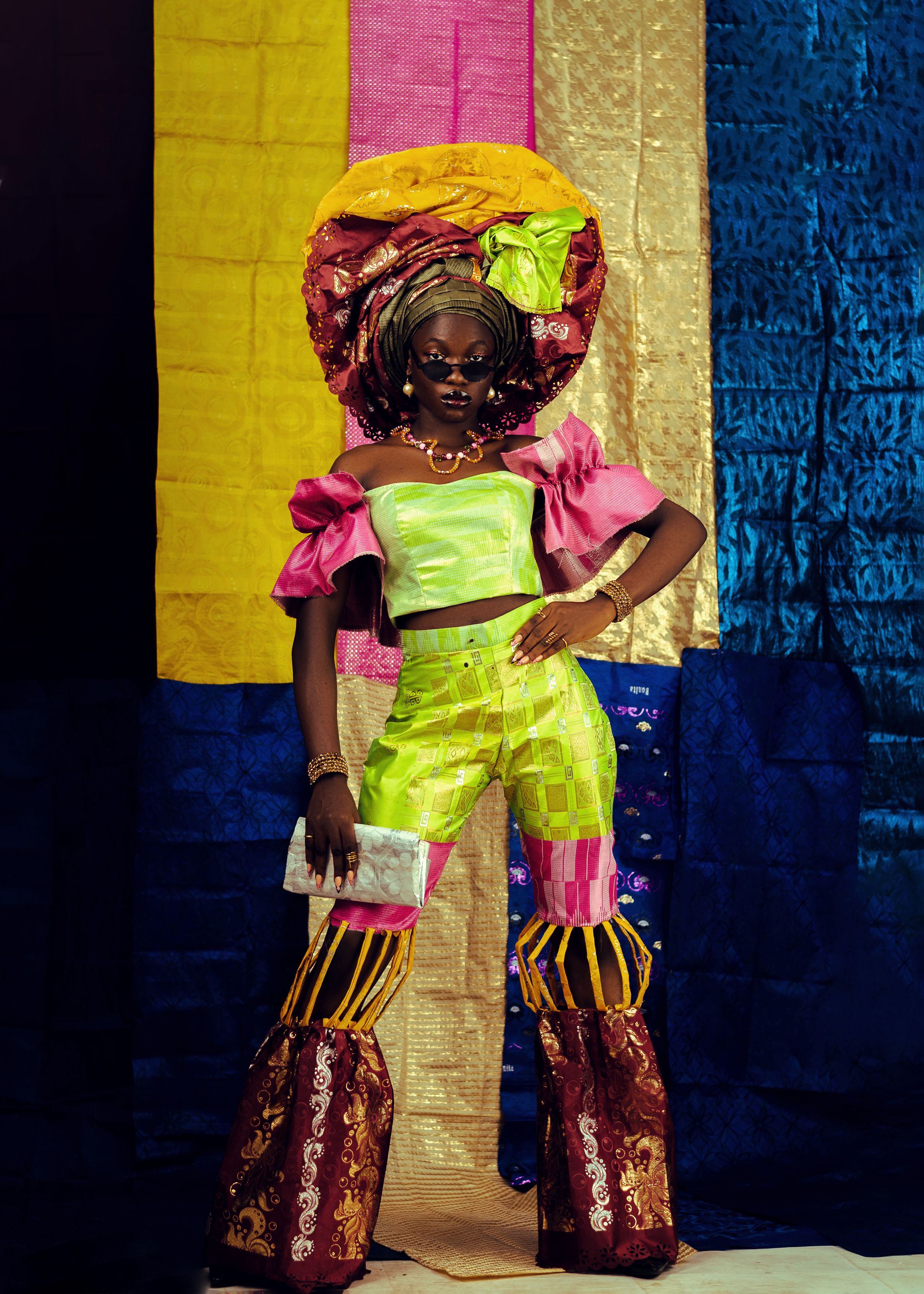 Colorful African fashion featuring a bold outfit with a traditional head wrap and sunglasses.