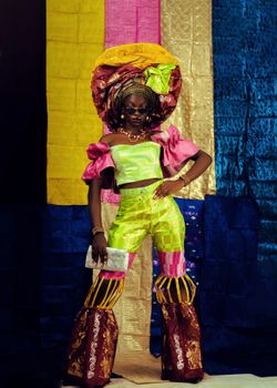 Colorful African fashion featuring a bold outfit with a traditional head wrap and sunglasses.