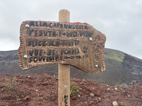 Wooden sign post overlooking Pompeii from Mount Vesuvius hiking trail on a cloudy day.