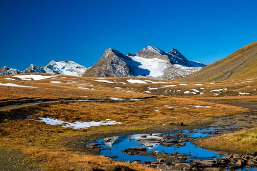 A breathtaking view of snow-capped mountains under a bright blue sky, capturing the serene beauty of nature.