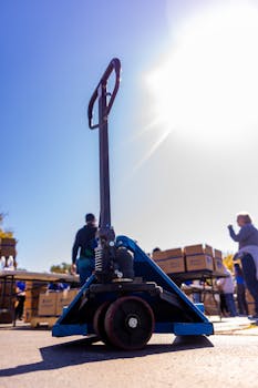 Pallet jack in focus during outdoor distribution event under bright sunlight.