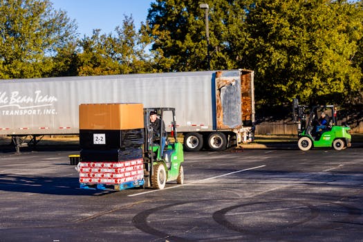 Forklift operators loading pallets onto a truck outdoors on a sunny day. Efficient warehouse logistics in action.
