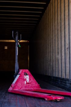 Red pallet jack inside an empty truck trailer, showcasing industrial transport equipment.