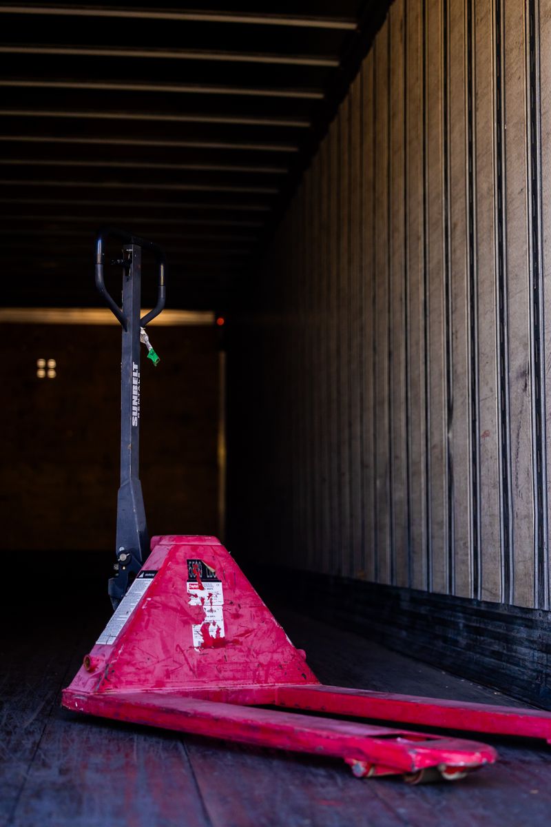 Red pallet jack inside an empty truck trailer