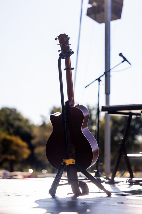 Free An acoustic guitar on an outdoor stage under bright sunlight, ready for a performance. Stock Photo