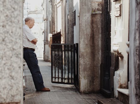 An elderly man contemplates quietly in a cemetery alleyway in Buenos Aires.
